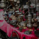 Assortment of antique metal items on a vibrant red tablecloth, showcasing intricate designs.