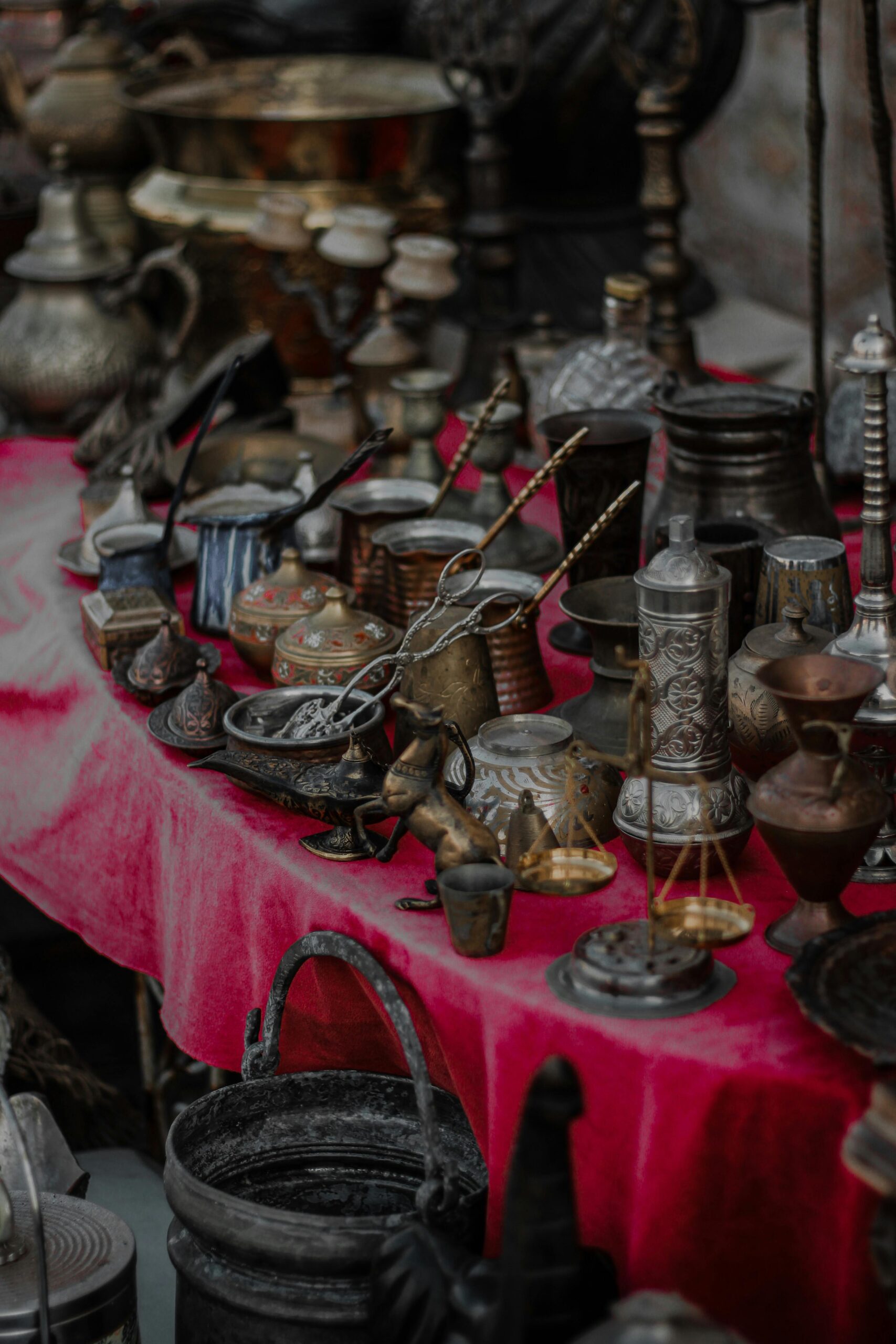 Assortment of antique metal items on a vibrant red tablecloth, showcasing intricate designs.